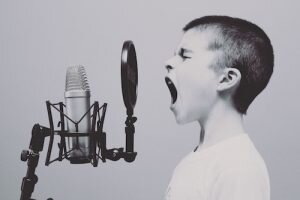 boy singing on microphone with pop filter.